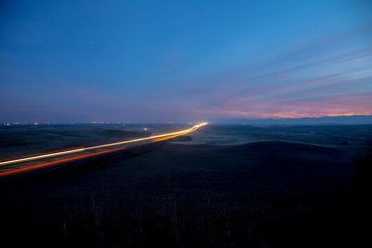 Lights streaming down highway just before dark. Long exposure of highway traffic under a blue and purple sunset.