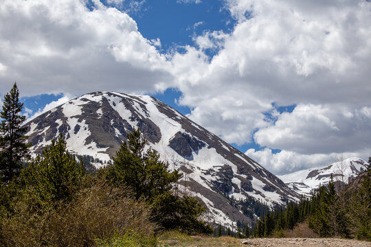 Snowy Rocky Mountain with blue sky and puffy clouds