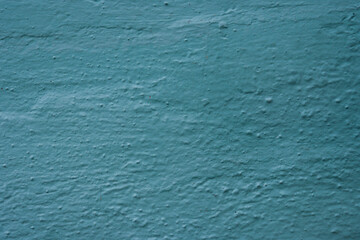Uneven rough texture of turquoise plaster.