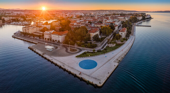 Zadar, Croatia - Aerial panoramic view of the old town of Zadar by the Adriatic sea with The Greeting to the Sun monument, Zadar skyline, sea organ, blue sky and golden rising sun on a summer morning