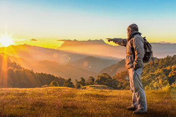 Fototapeta na wymiar Successful young male hiker with backpack enjoying sunrise on peak mountain.