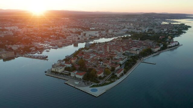Zadar, Croatia - 4K Flying towards and descending to the old town of Zadar with The Greeting to the Sun monument, Zadar skyline, sea organ, blue sky and golden rising sun on a summer morning