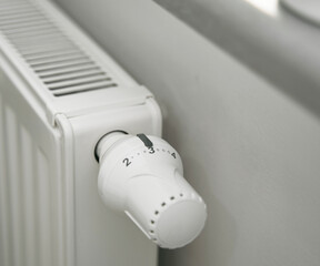 Close-up of turning down the thermostat on a radiator to save energy due to heating cost price...