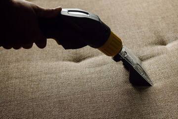 Close-up of a furniture vacuum cleaner and a dirty sofa. Cleaning and house cleaning, housekeeper...