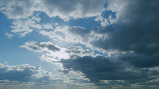 Suns rays pass through the white clouds against the blue sky. Open blue sky cloudscape. Timelapse.