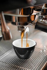 Vertical closeup of coffee pouring into a cup from the machine