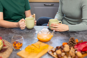 Two girls drink delicious, fragrant tea with a pie. Tea party with sea buckthorn tea and pumpkin pie. The pie cut into pieces lies on a wooden board. Two women, friends, lgbt