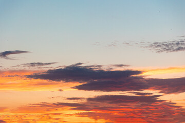 Golden sunset in the sky with clouds. Dark epic sky with a copy space. Beautiful heaven and cloudscape