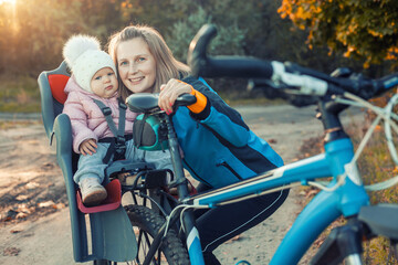 Young beautiful mother with small baby on bicycle.