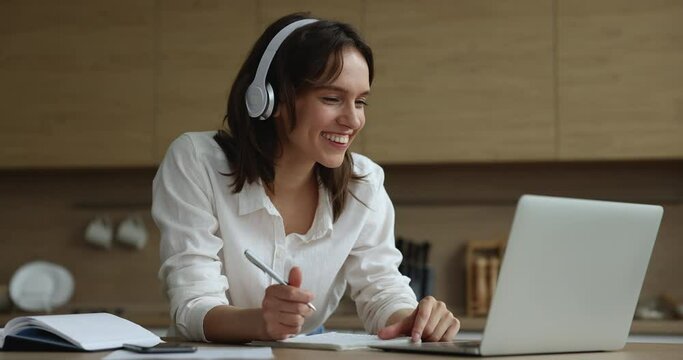 Young woman in headphones e-learning with tutor at home, greeting on-line teacher start or finish remote class, gain new knowledge, improve foreign language skills. Education, tuition, tech concept