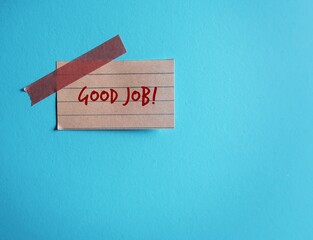 Note stick on blue copy space background with words GOOD JOB, concept of positive self talk,...