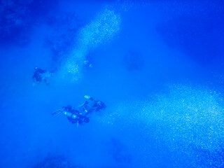 Fototapeta na wymiar divers with many bubbles in the blue deep of the sea