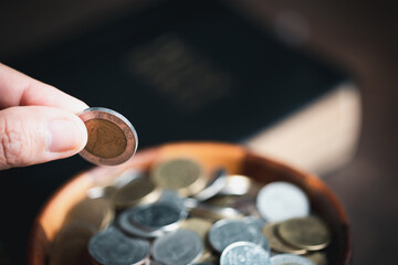 One tenth or tithe is basis on which Bible teaches us to give one tenth of first fruit to God. coins with Holy Bible. Biblical concept of Christian offering, generosity, and giving tithes in church.