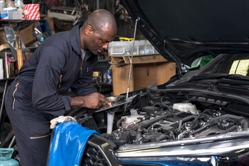 Fototapeta na wymiar African black car mechanic working with car maintenance in auto repair garage, Car Mechanic Concept