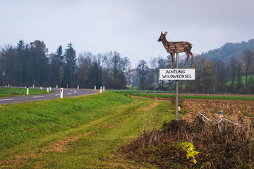 Achtung Wildwechsel: "liebes" Schild neben einer Landstrasse im Herbst bei nebeligem Wetter
