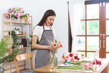 Florist concept, Female florist arranging colorful gerbera in vase with happiness at flower shop