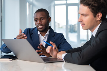 Inspired African American businessman wearing formal suit talking to colleague