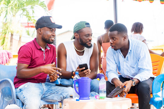 image of african guys with smartphone and enjoying conversation outside- seated black men having fun