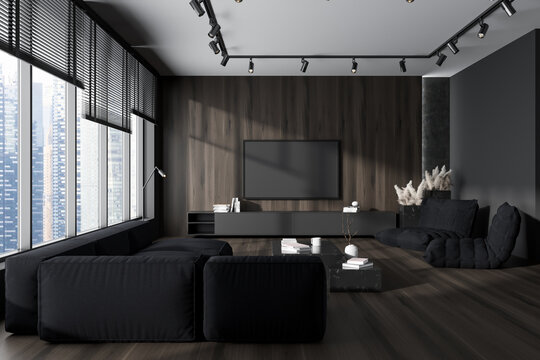 Dark chill interior with couch and armchairs, drawer and tv, panoramic window