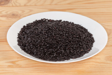 Raw long-grained black rice on a white dish