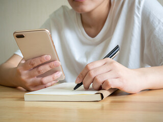 Close up female sitting at desk, holding phone in hand.