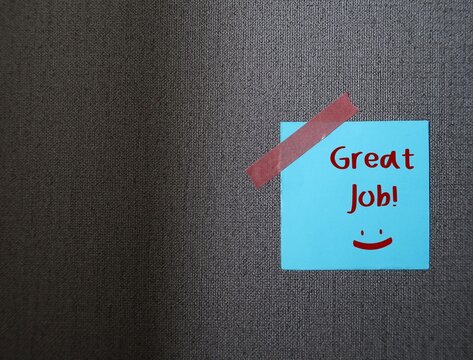 Blue note stick on grey copy space background with words GREAT JOB, concept of positive self talk, praise encouragement note from boss, teacher or clients to express admiration for well done job