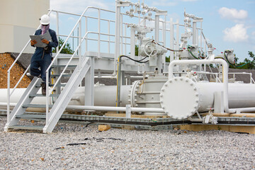 Male worker inspection at steel long pipes and pipe elbow in station oil factory during refinery valve of visual check record pipeline