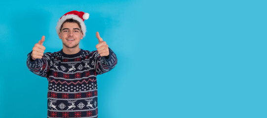 isolated young man with christmas sweater and santa claus hat sad with okay and approving hands