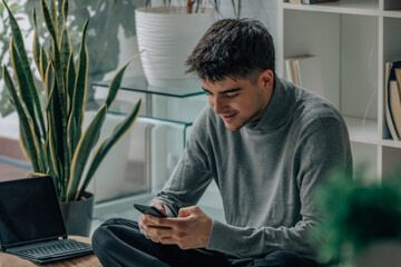 young man or teenager at home with mobile phone