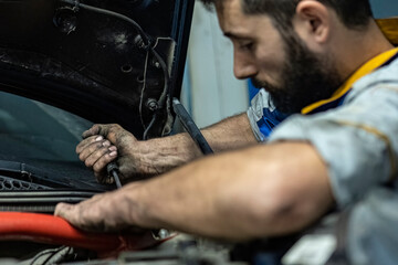 Mechanic with dirty hands works on the engine