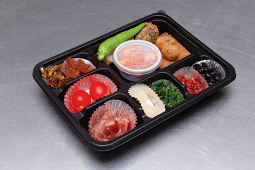 A delicious-looking lunch box with a variety of side dishes, fruits and tempura
