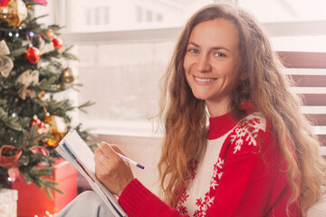 Woman writing shopping list, Christmas letter or wish list