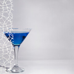 Drink in cocktail glass. Blue vibrant color.White curtain lace aesthetic design. Night life concept. Bar  mystic atmosphere. Party holidays design idea with liquor