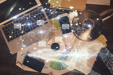 Envelop hologram drawing over computer on the desktop background. Top view. Double exposure. Technology concept.