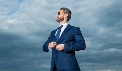 Professional man looking aside sky background. Grizzled man wearing sunglasses. Serious man