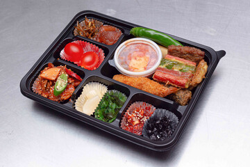 A delicious-looking lunch box with a variety of side dishes, fruits and tempura