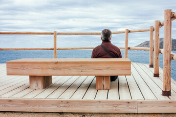 A seated man contemplates the sea.