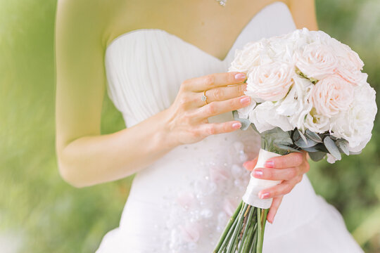 Bride's hand touching the bouquet with fingers at the wedding