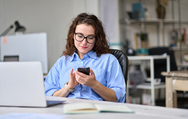 Young business woman employee looking at smartphone device using cellphone mobile cell texting...