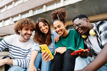 Group of university student friends sitting together using mobile phones to share content on social media - obrazy, fototapety, plakaty