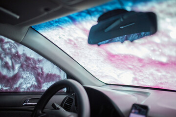 Man washing his car, using pink active foam on self service washing, contactless high pressure...