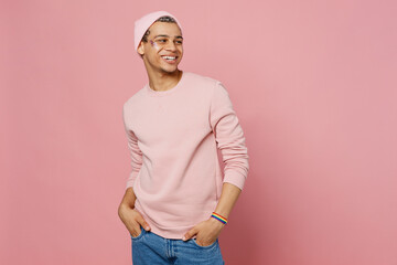 Side view young happy smiling fun gay man wear sweatshirt hat look aside on workspace area mock up isolated on plain pastel light pink color background studio portrait. Lifestyle lgbtq pride concept.
