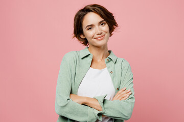Young smiling happy cheerful woman 20s she wear green shirt white t-shirt hold hands crossed folded...