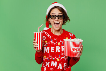 Young fun woman in 3d glasses knitted xmas sweater Santa hat watch movie film hold bucket of...