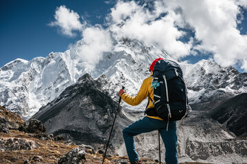 Solo tourist with travel backpack walk along high altitude mountain track. Outdoor mountains explorer traveling among snowy summit rock