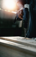 Closeup craftman hands using electronic drill at shop.