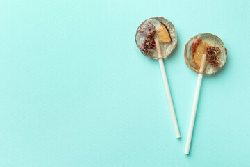 Sweet colorful lollipops with berries on turquoise background, flat lay. Space for text
