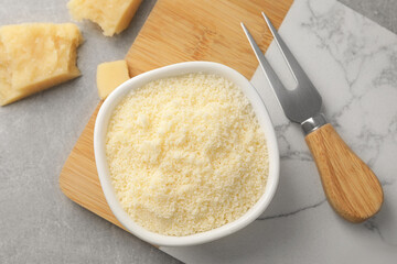 Parmesan cheese with fork on grey table, flat lay