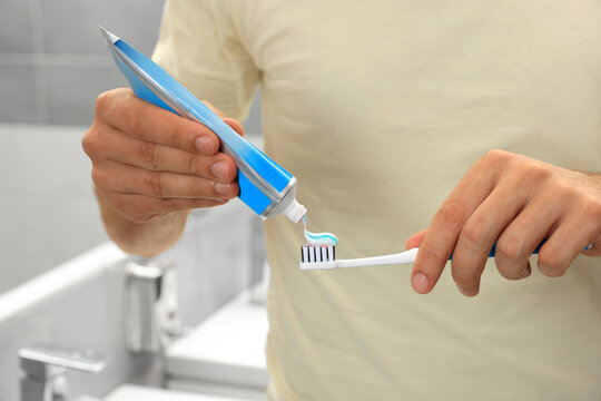 Man applying toothpaste on brush in bathroom, closeup