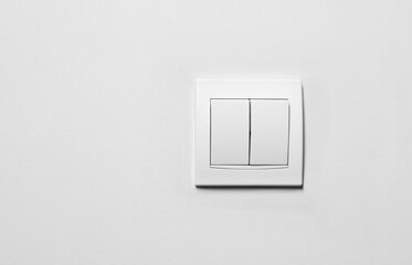 Modern plastic light switch on white wall, space for text